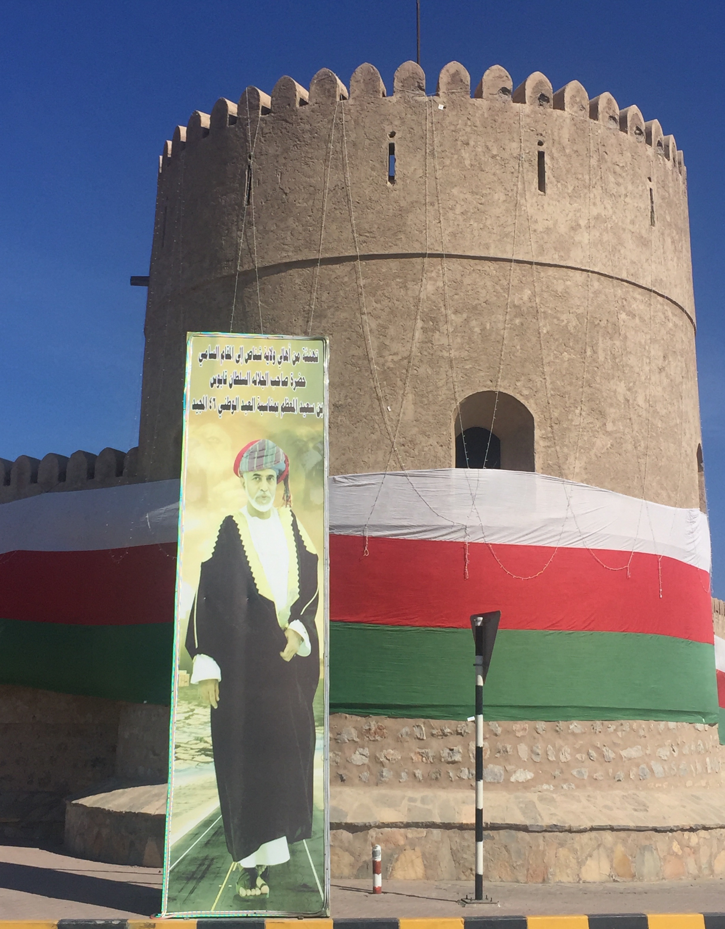 صورة عملاقة لجلالة السلطان والعلم العماني على حصن شناص