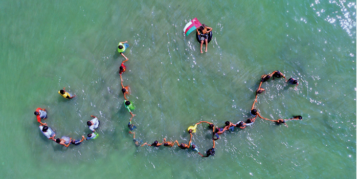 Youngsters join hands in the sea to spell out Oman in Arabic
