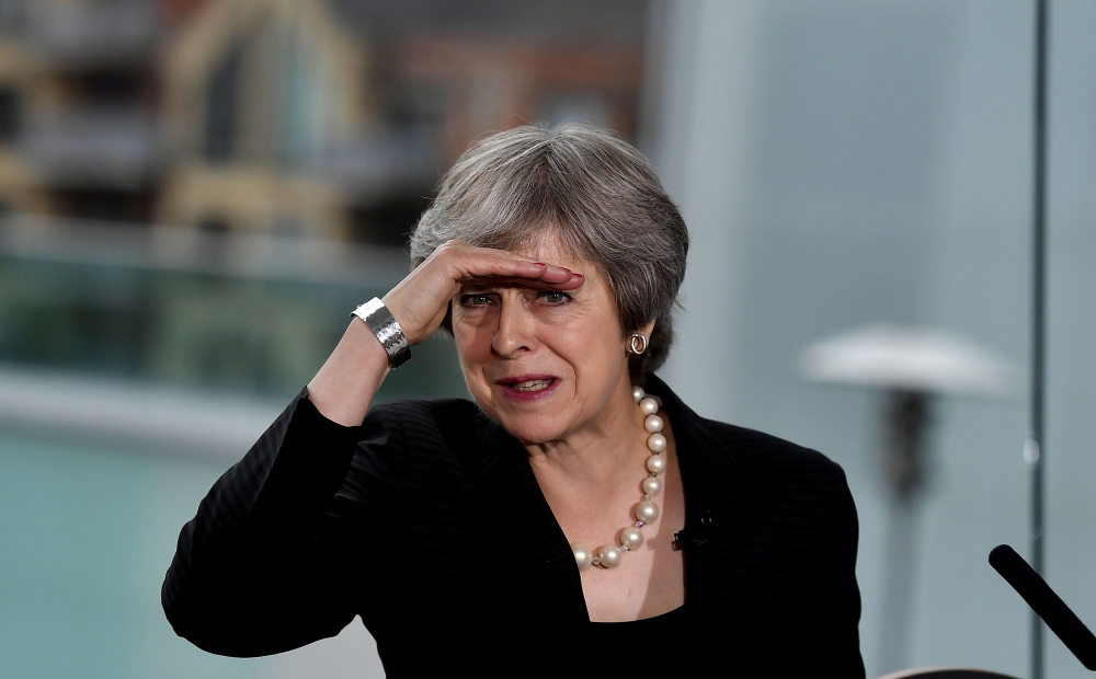 UK's May survives, weakened and with an exit date